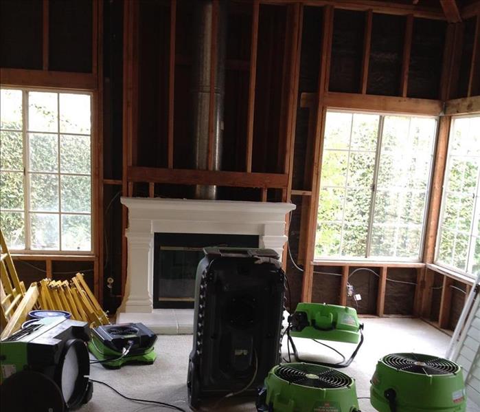 living room with removed walls and drying equipment on the floors 