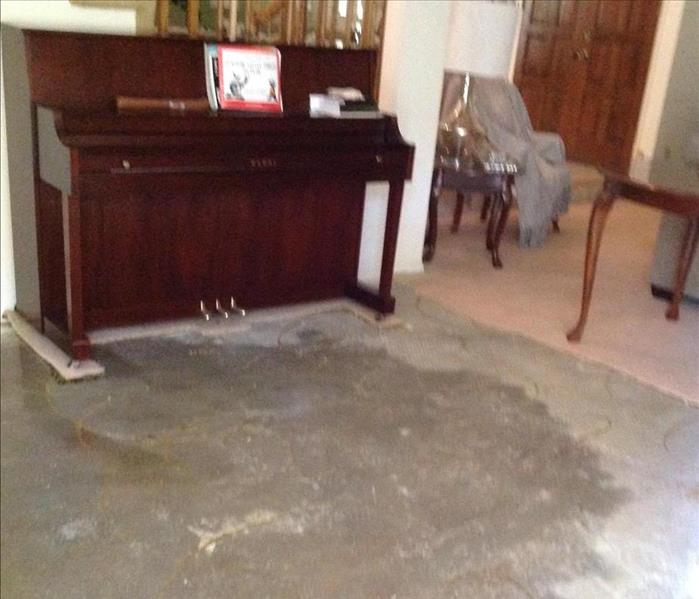 cement floor with water damage and a piano next to stairs 