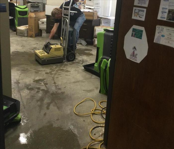 grey floors with water with a man next to a green machine 