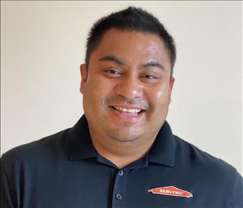 Male employee with black hair smiling in front of a white background 