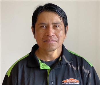 Male employee with black hair smiling in front of a white background 