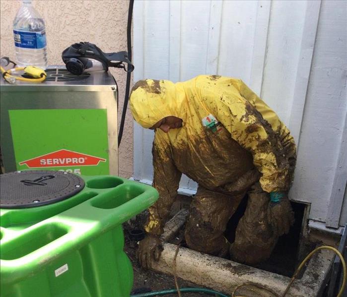 male wearing a suit with mud all over him next to a house 