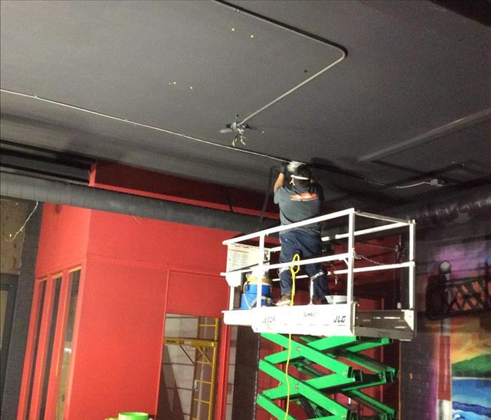 man on a machine cleaning the black ceilings 