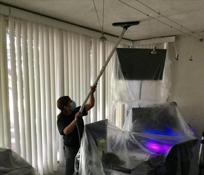 female holding a cleaning devince onto ceiling 