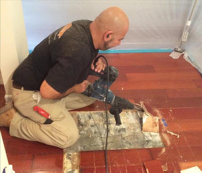 male in black shit is removing floors with a tool