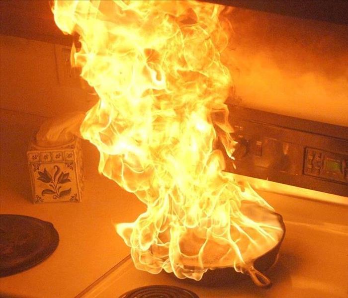 a pan on fire on top of a white stove